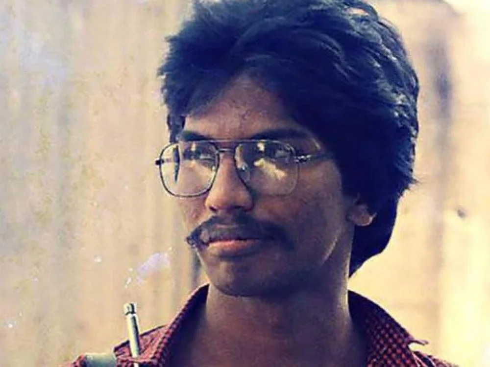 Portrait de Thileepan, lunettes et chemise à carreaux.